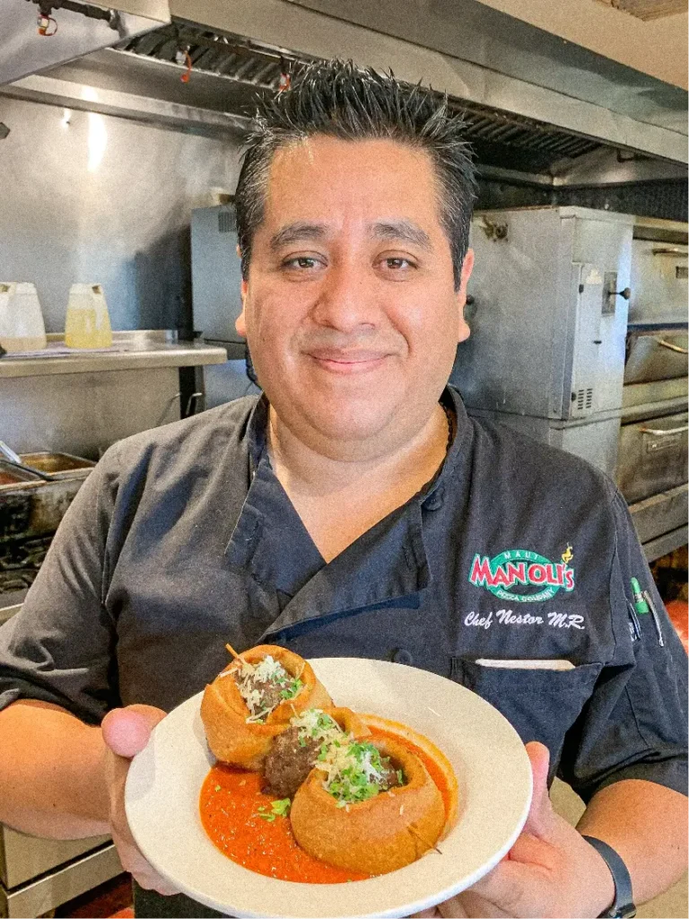 Head chef at Manoli’s Pizza Company preparing signature dishes in Wailea Maui restaurant kitchen focused on fresh island-inspired cuisine.